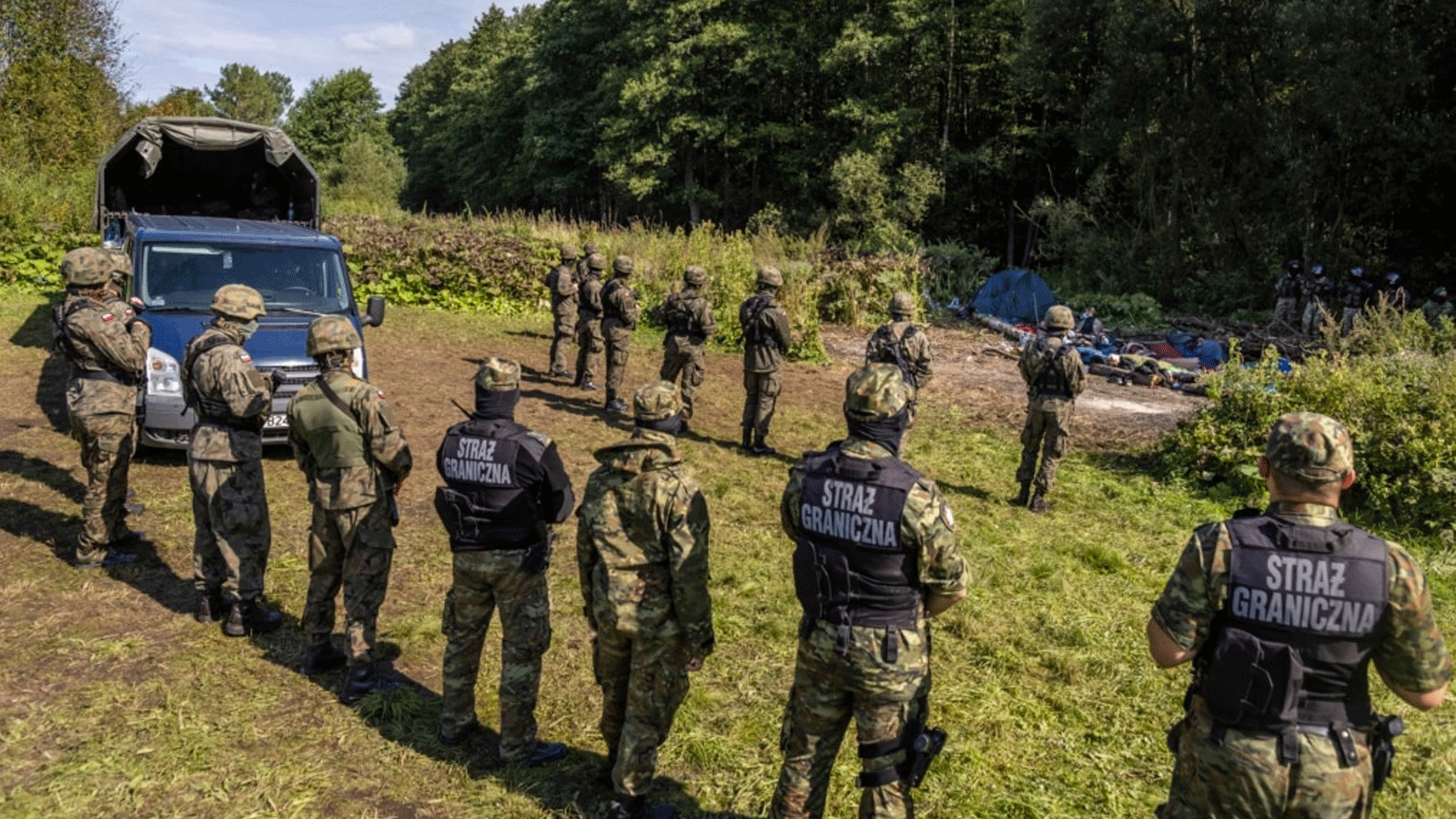 الشرطة البولندية قبالة الحدود مع بيلاروسيا (على اليمين)، حيث يتواجد مهاجرون عالقون في العراء بالقرب من قرية أوسنارز جورني البولندية