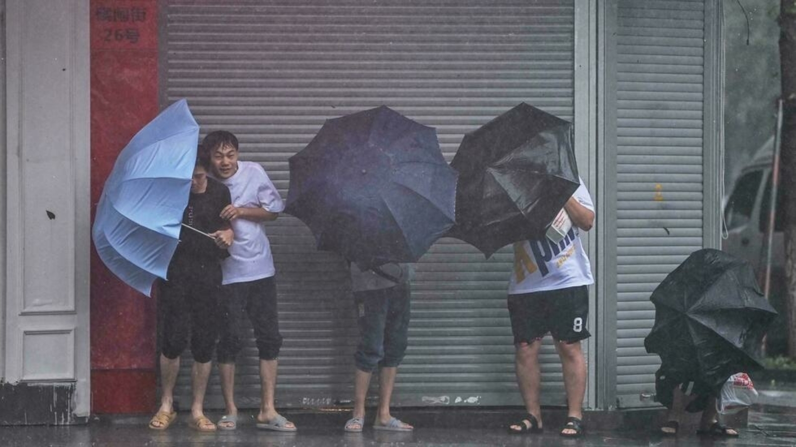 الناس يختبئون من المطر والرياح في نينغبو في 25 تموز/ يوليو 2021، حيث ضرب إعصار الساحل الشرقي للصين.