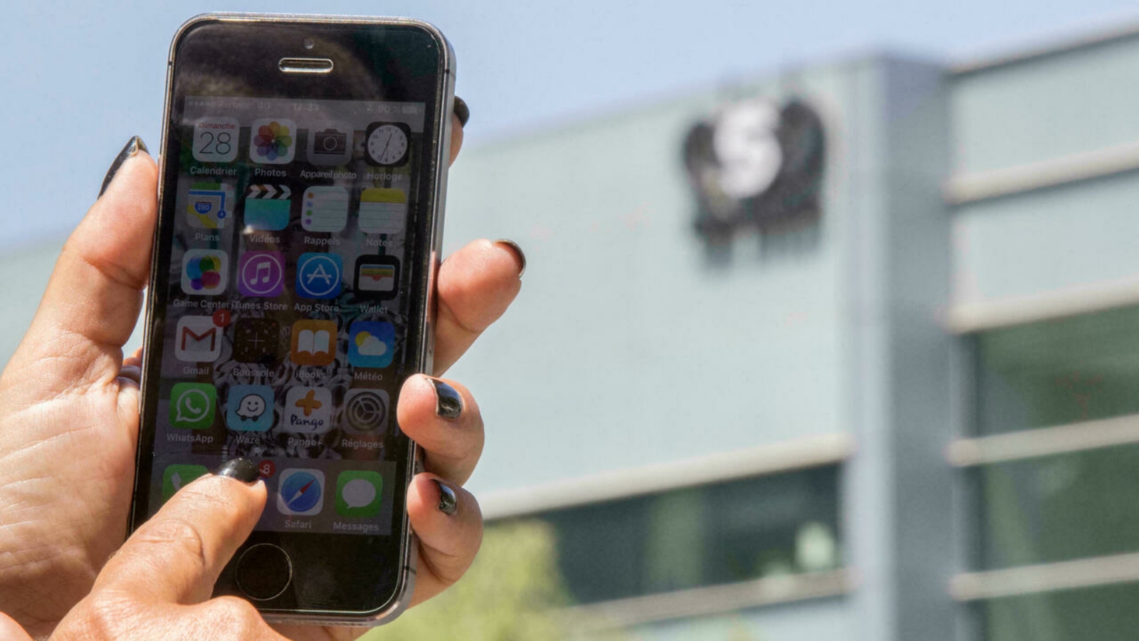 امرأة إسرائيلية تستخدم هاتف أيفون الخاص بها أمام المبنى الذي يضم مجموعة أن أس أو الإسرائيلية.