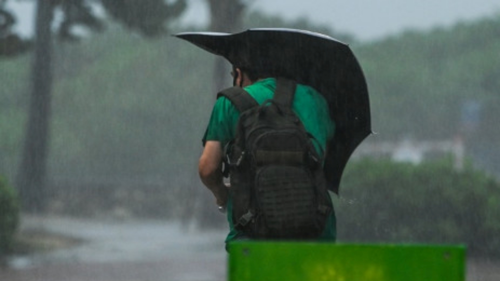 رجل يقف تحت الأمطار الغزيرة فيما تتحرك ميندي باتجاه الشمال الشرقي بسرعة حوالي 21 ميلاً (33 كيلومترًا) في الساعة وكان من المتوقع أن تحافظ على هذا المسار في الأيام المقبلة.