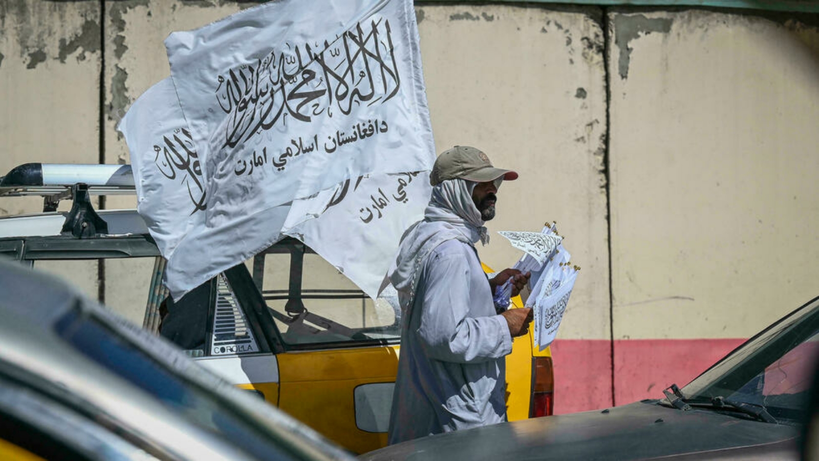 رجل يبيع علم الدولة الإسلامية الذي اعتمدته طالبان علمًا جديدًا لأفغانستان.