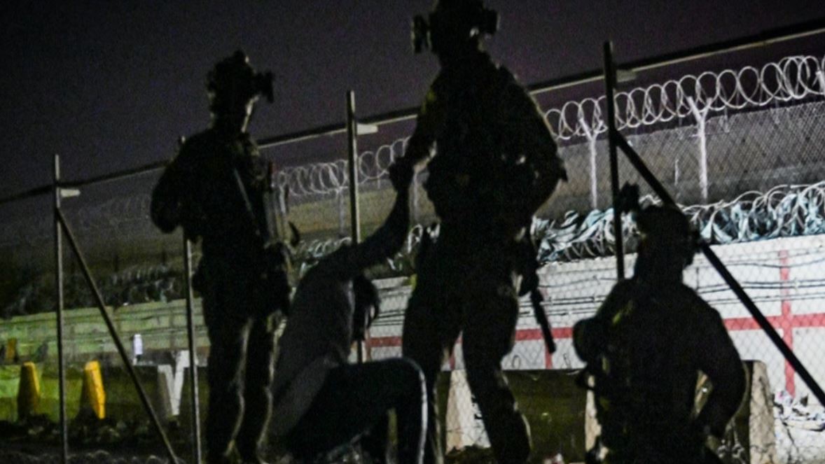 جنود بريطانيون يساعدون أفغانياً على تسلق جدار بالقرب من مطار كابول في 22 أغسطس 2021
