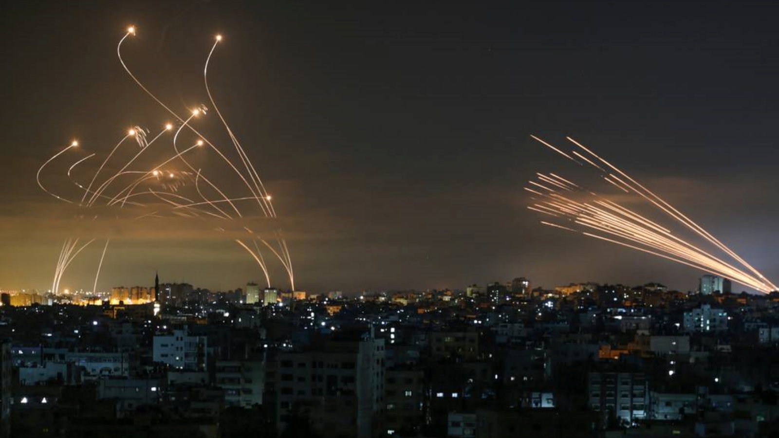 نظام دفاع صاروخي إسرائيلي من طراز القبة الحديدية، يسار، يعترض الصواريخ، يمين، التي أطلقها مسلحو حماس باتجاه جنوب إسرائيل من بيت لاهيا في شمال قطاع غزة. بتاريخ 14 أيار/ مايو 2021.