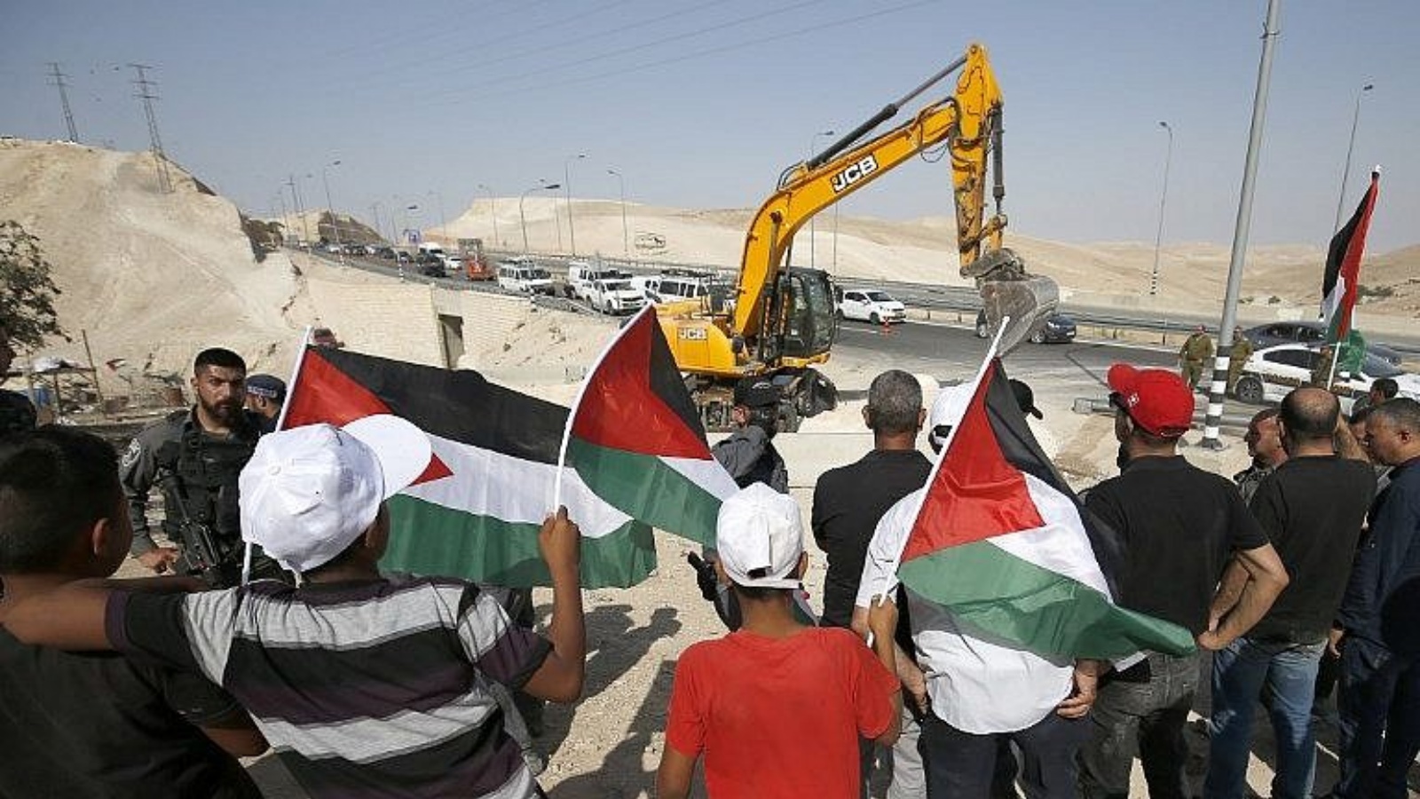 متظاهرون يلوحون بالأعلام الفلسطينية احتجاجًا على الهدم المرتقب لقرية الخان الأحمر البدوية في الضفة الغربية. (أرشيفية)