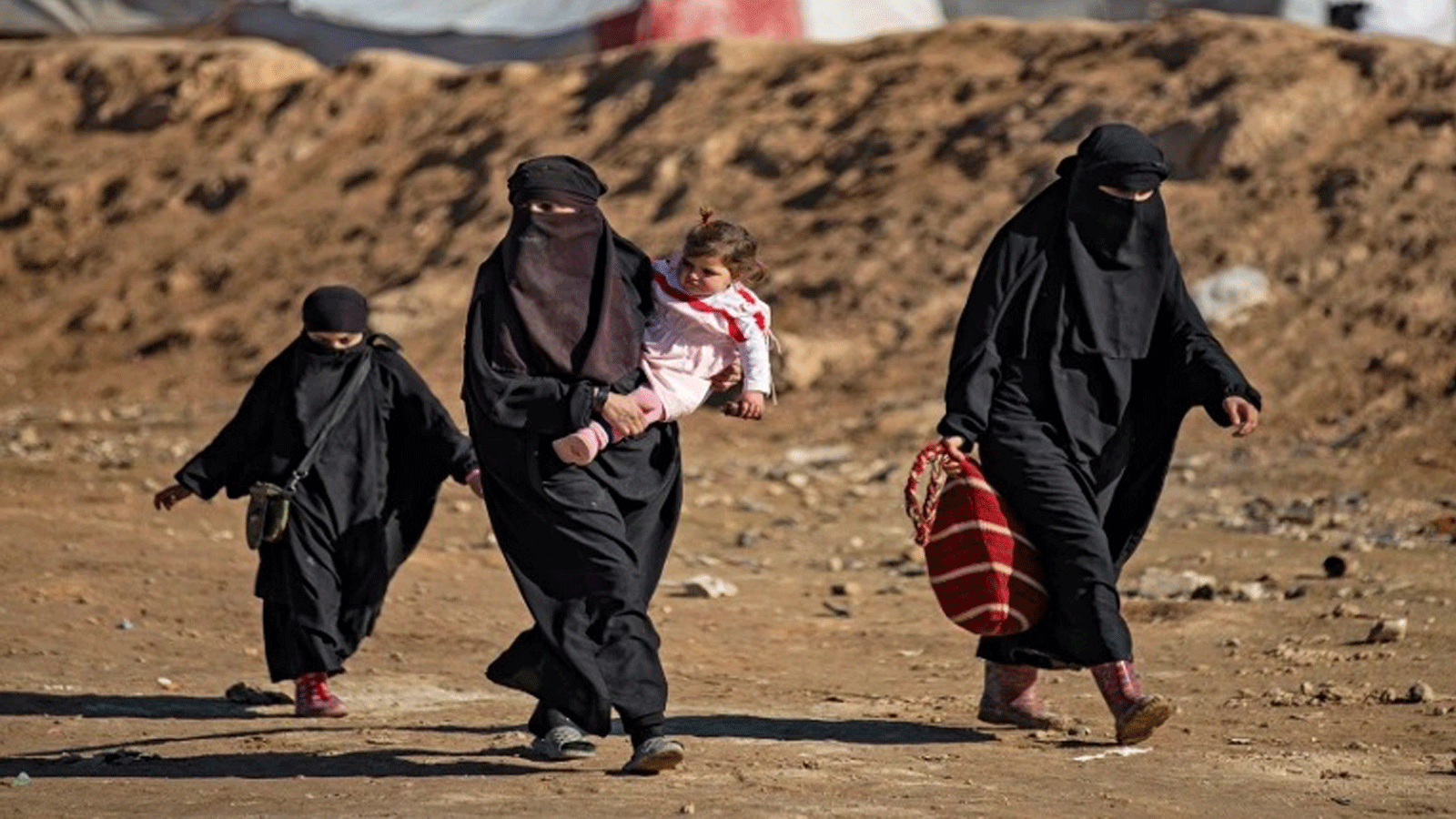 نساء وأطفال يمشون بالقرب من مخيم الهول الذي يديره الأكراد للنازحين السوريين في صورة التُقِطَت بتاريخ 14 كانون الثاني/ يناير 2020