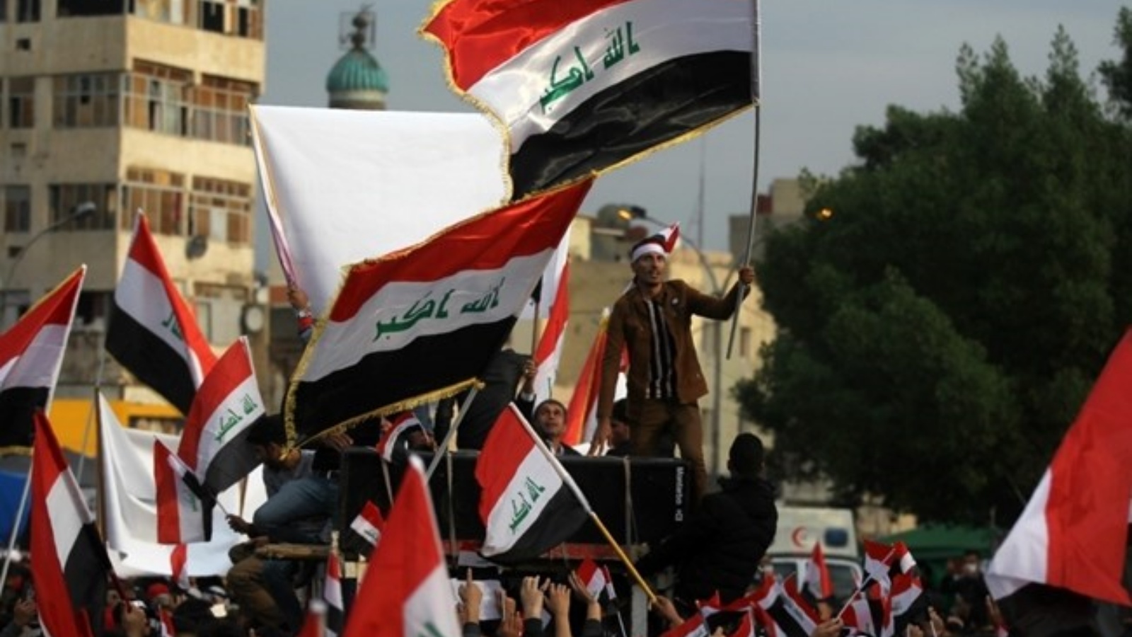 عراقيون يحملون علم بلادهم في تظاهرة في ساحة التحرير، بغداد. (أرشيفية)
