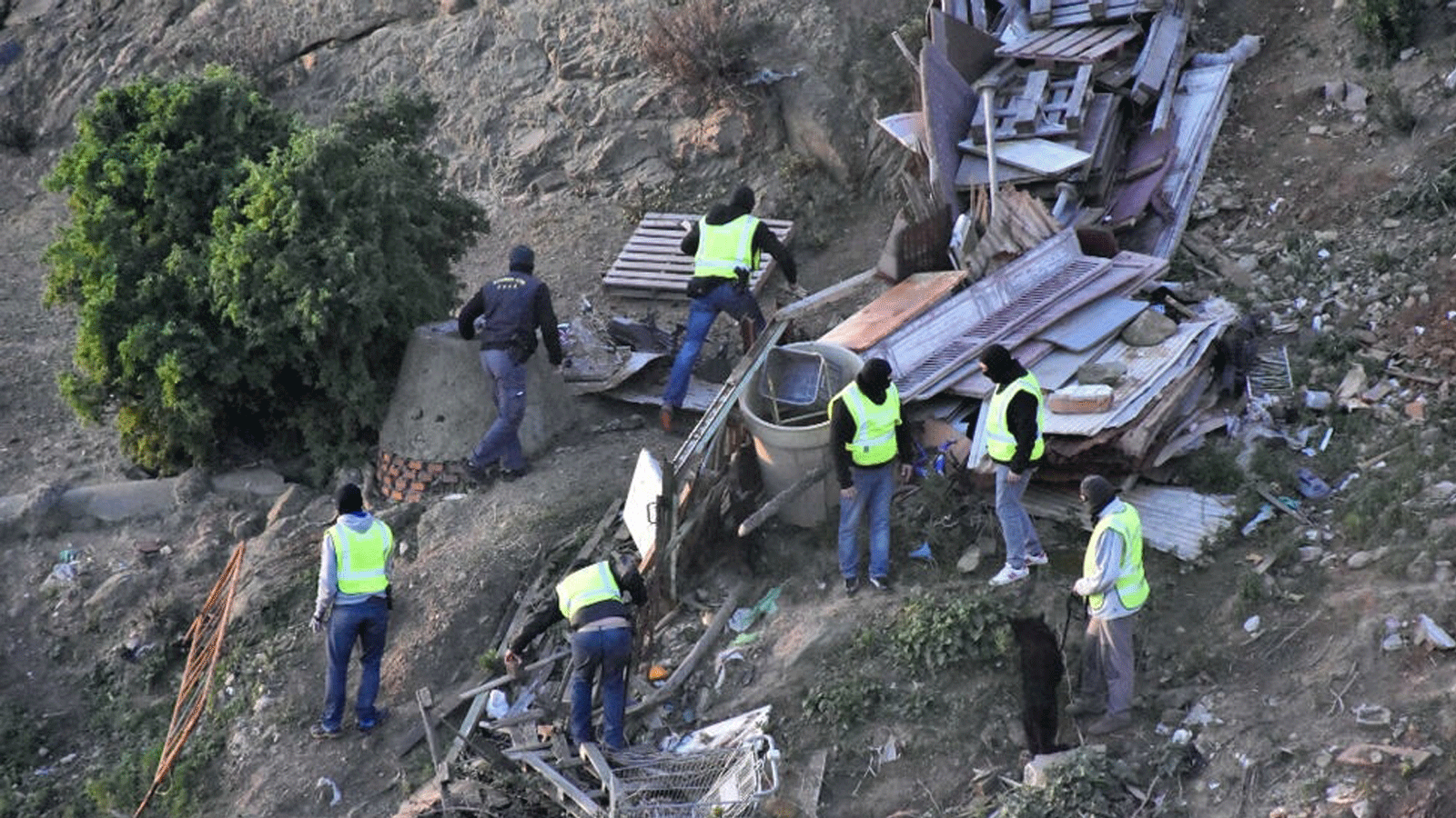 رجال ملثمون من الحرس المدني الإسباني يقومون بعمليات تفتيش في قطعة أرض خالية بعد اعتقال اثنين من الجهاديين المشتبه بهم، في جيب سبتة بشمال أفريقيا. في 13 يناير / كانون الثاني 2017