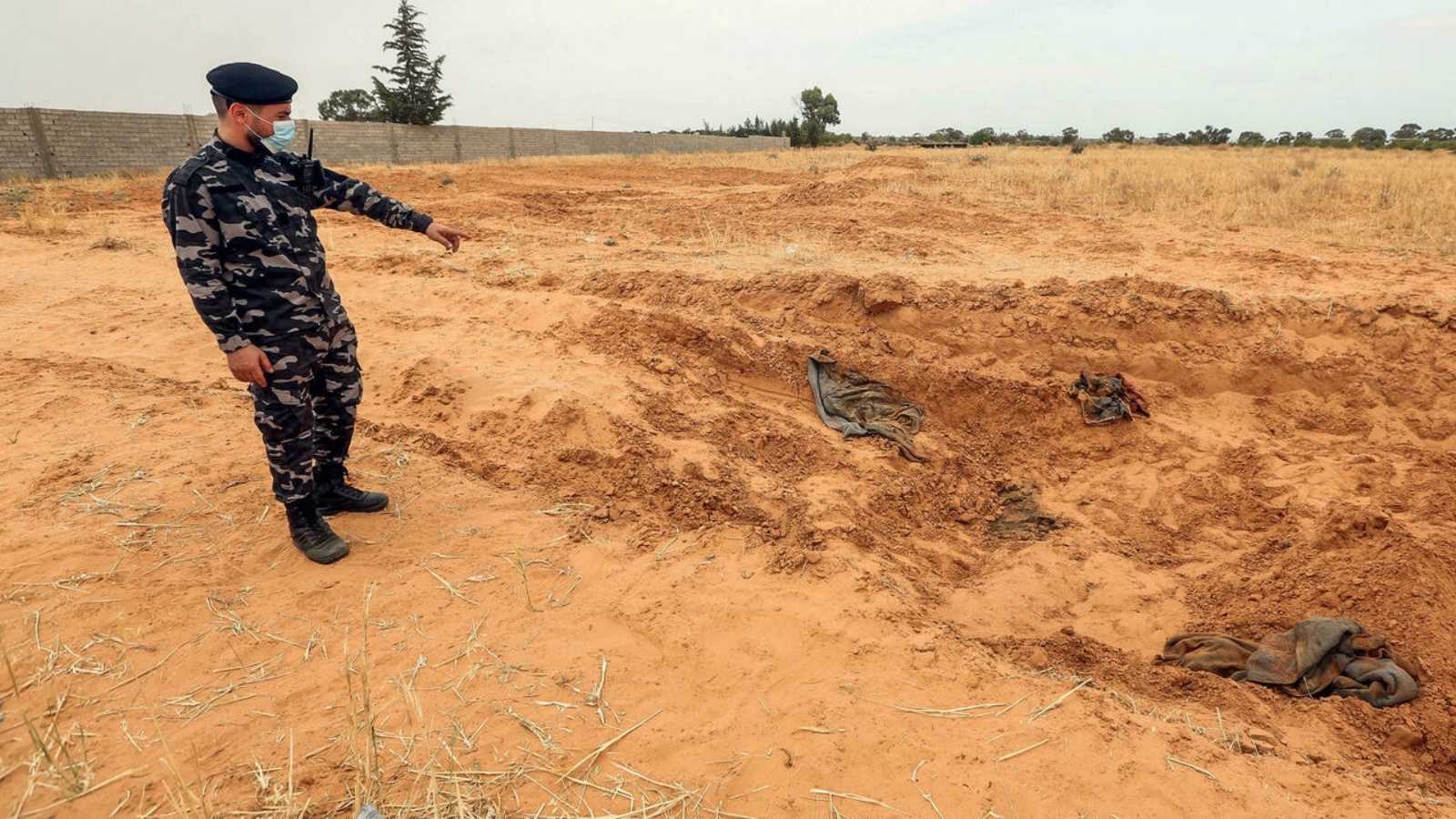 أحد عناصر القوات الأمنية التابعة لوزارة الداخلية في حكومة الوفاق يتفقد موقع مقبرة جماعية في بلدة ترهونة، جنوب شرق العاصمة طرابلس، ليبيا. حزيران / يونيو 2020.