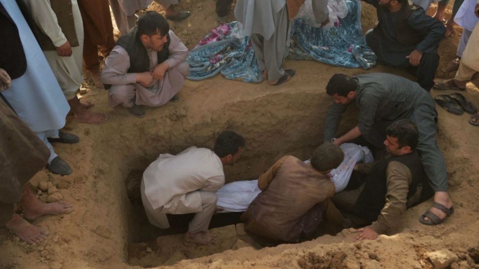أفراد أسرة يدفنون جثة ضحية تفجير انتحاري في مسجد شيعي في أفغانستان. في 9 تشرين الأول/أكتوبر 2021.