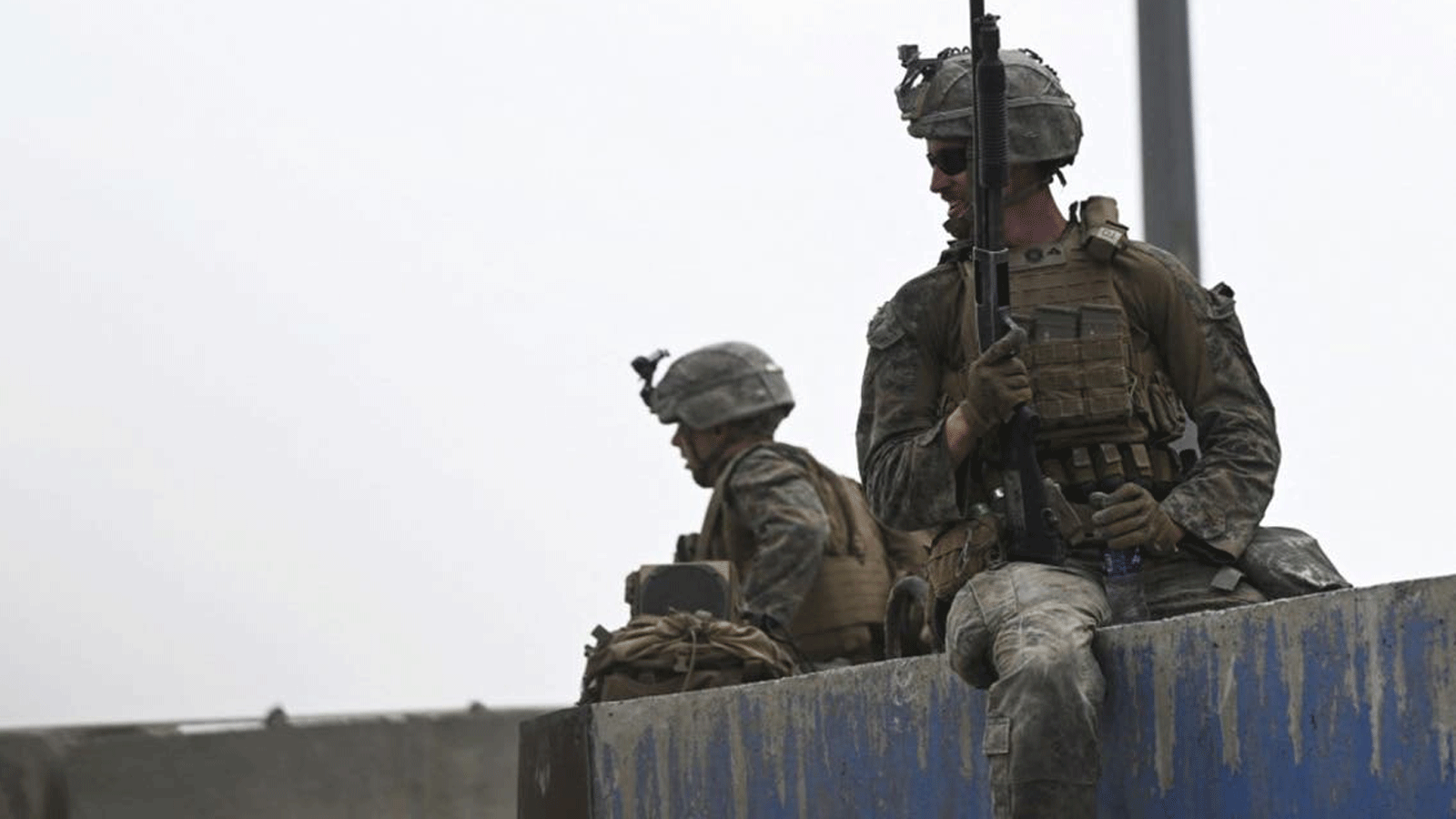 جنود أمريكيون يجلسون على جدار بينما يتجمع الأفغان على جانب طريق بالقرب من الجزء العسكري من مطار كابول في 20 آب/أغسطس 2021