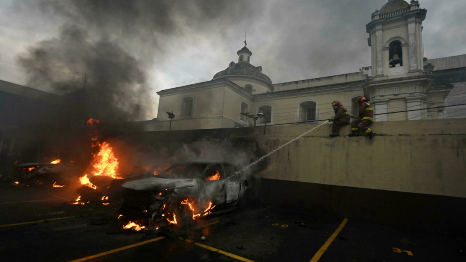 رجال الإطفاء يحاولون إخماد سيارة مشتعلة في موقف السيارات بمبنى الكونغرس في غواتيمالا، حيث اشتبك جنود سابقون محتجون مع شرطة مكافحة الشغب.