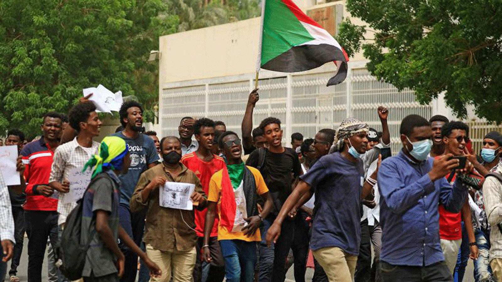 محتجون سودانيون يرددون هتافات ويلوحون بالعلم الوطني لبلادهم أثناء مسيرة في العاصمة الخرطوم.