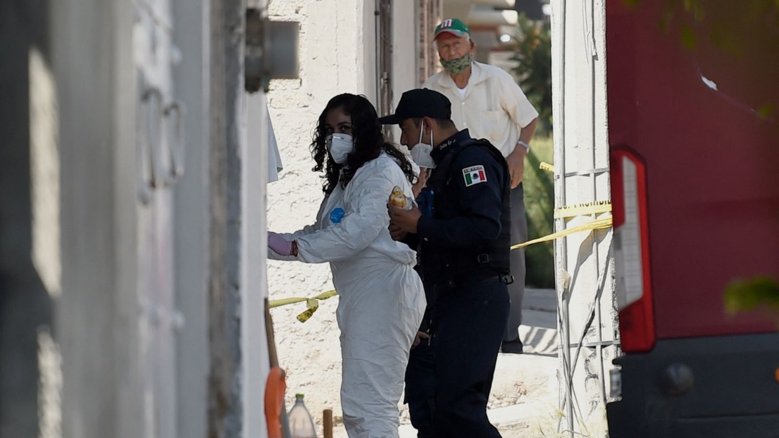 شرطي وطبيبة شرعية يدخلان منزل قاتل متسلسل مزعوم في ولاية المكسيك، المكسيك. في أيار/مايو 2021