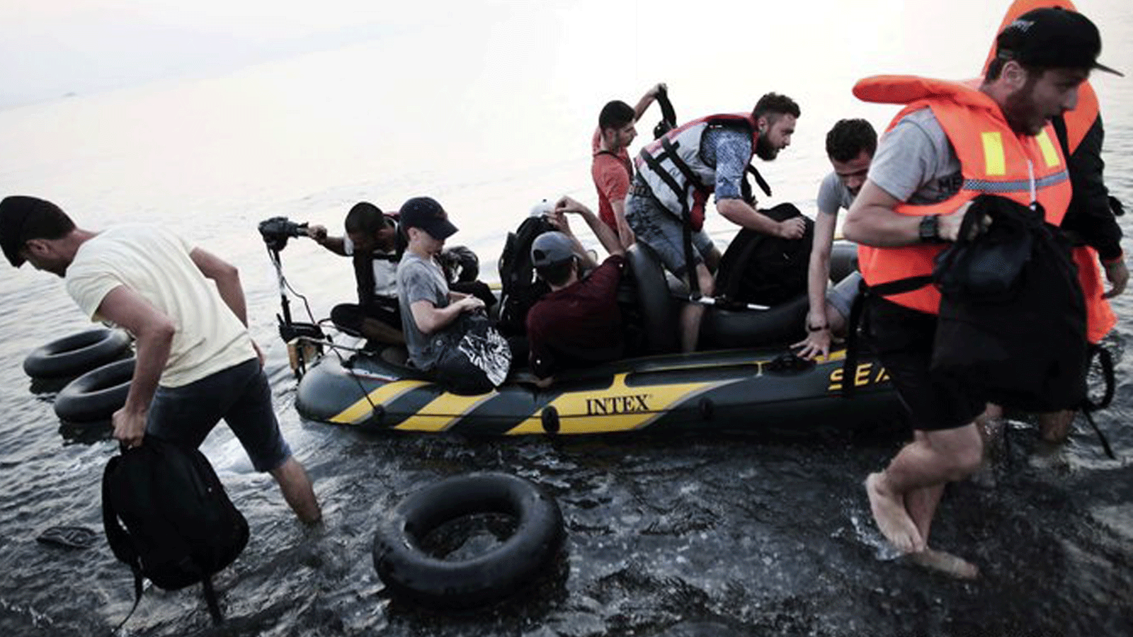 مهاجرون يخرجون من قارب قابل للنفخ بعد وصولهم إلى جزيرة كوس اليونانية.11 آب/أغسطس 2015