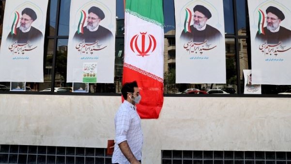 إيراني يمر قرب صور للرئيس الإيراني إبراهيم رئيسي في أحد شوارع إيران