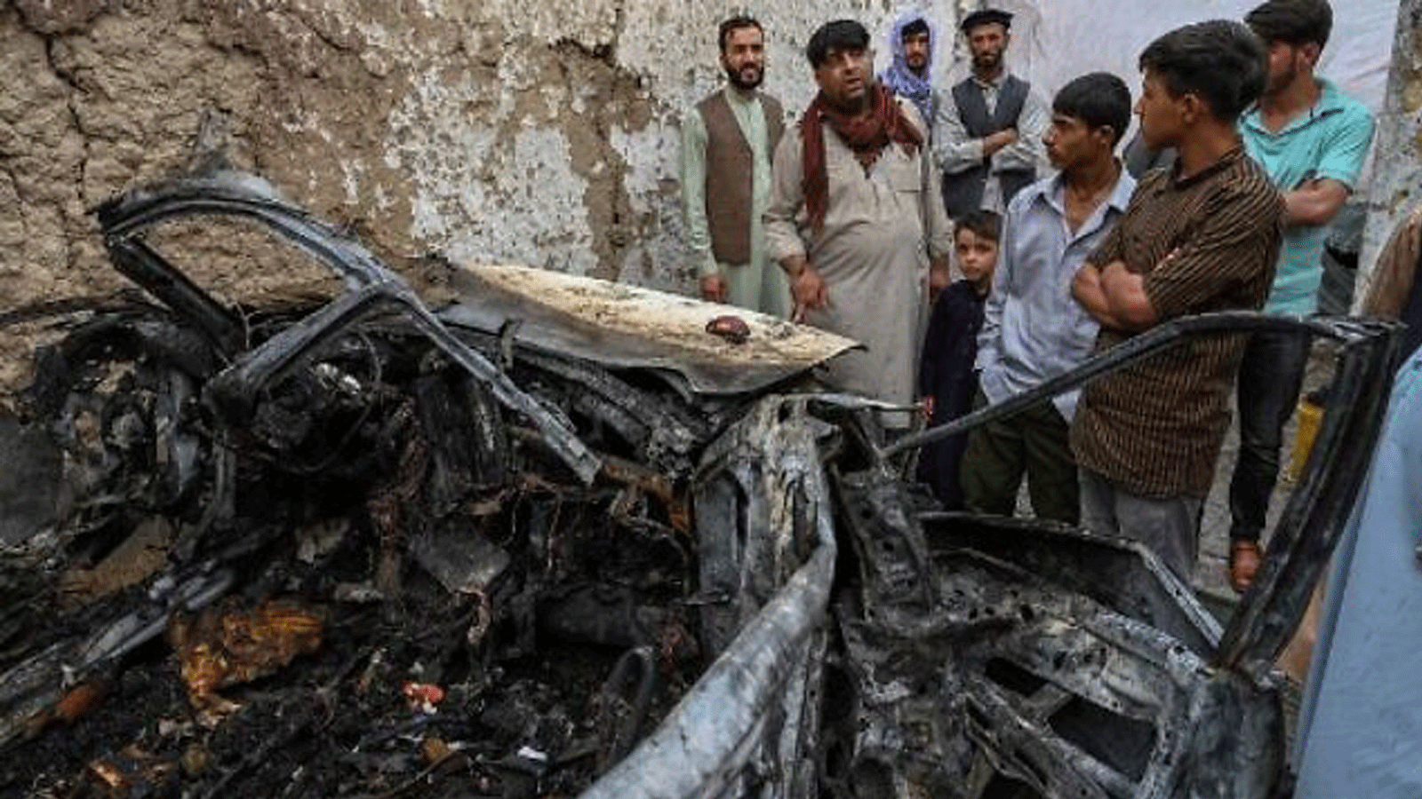 سكان أفغان وأفراد عائلات الضحايا يتجمعون بجوار سيارة مدمرة داخل منزل ، بعد يوم من غارة جوية أمريكية بطائرة بدون طيار في كابول في 30 أغسطس / آب 2021