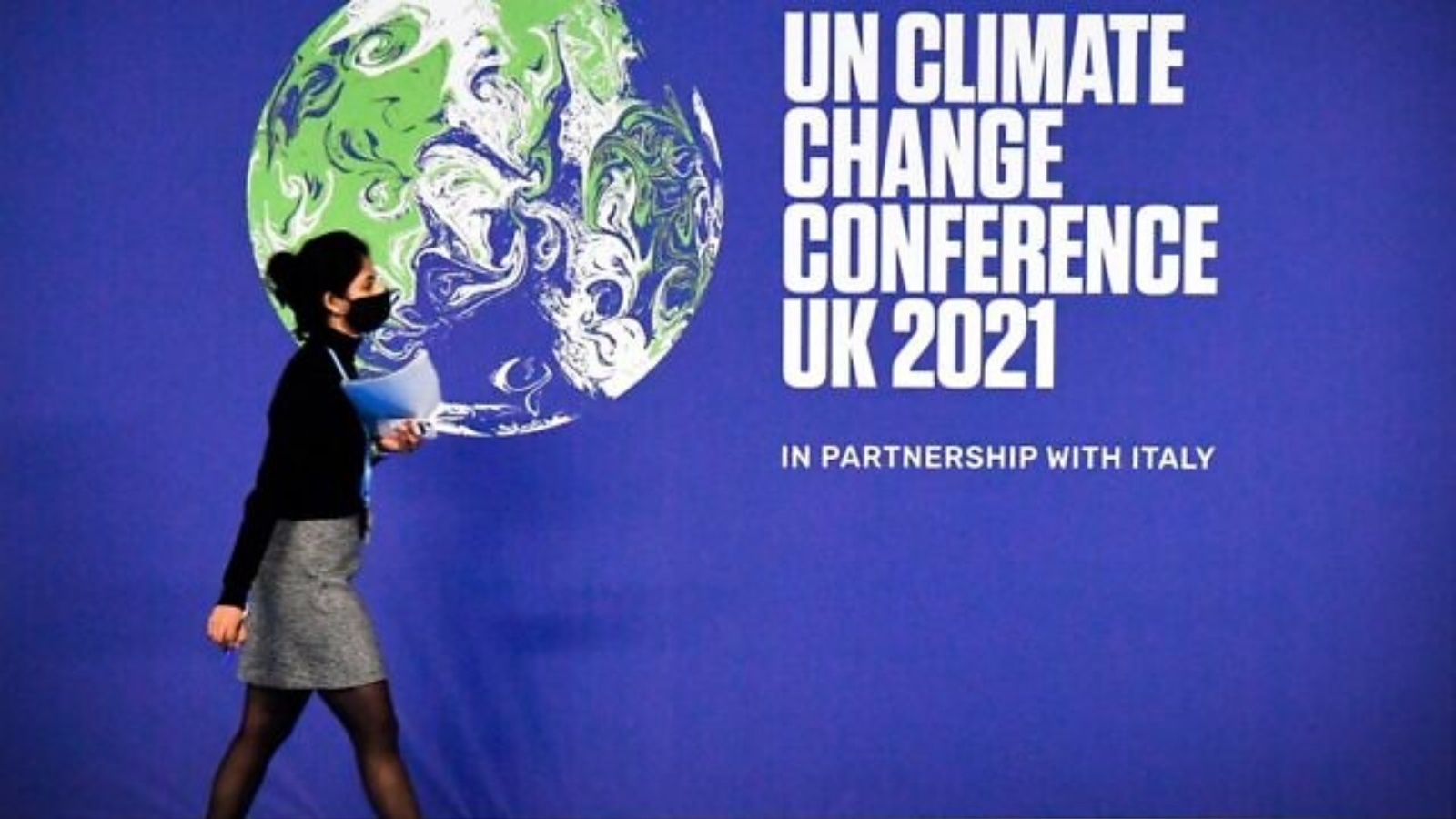 إحدى المشاركين تمر بجوار ملصق مؤتمر الأمم المتحدة لتغير المناخ كوب26 في اليوم الأول من المؤتمر في الحرم الجامعي للحدث الاسكتلندي (SEC) في غلاسكو، اسكتلندا. في 31 تشرين الأول/أكتوبر 2021.