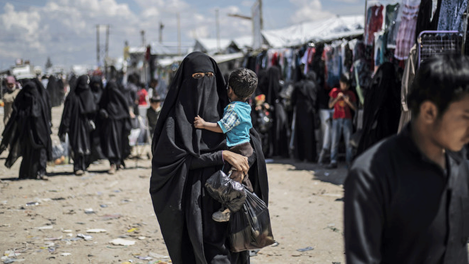 امرأة نازحة من محافظة دير الزور شرقي سوريا تحمل طفلها أثناء سيرها في مخيم الهول للنازحين بمحافظة الحسكة شمال شرقي سوريا.