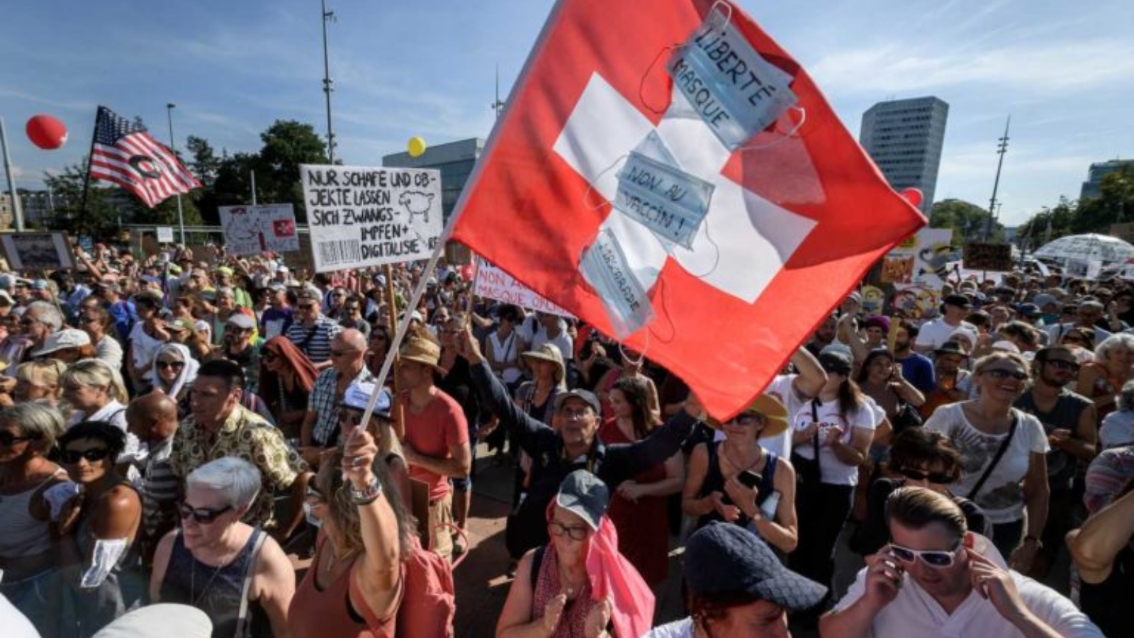 متظاهر يلوح بالعلم الوطني السويسري خلال احتجاج على إجراءات فيروس كورونا في جنيف. (أرشيفية)