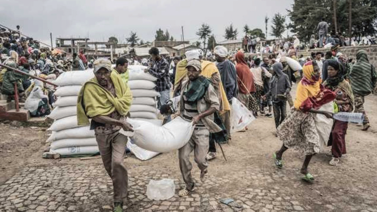 رجال يحملون كيسًا من القمح أثناء توزيع الغذاء من قبل برنامج الغذاء العالمي على النازحين داخليًا في ديبارك، إثيوبيا.
