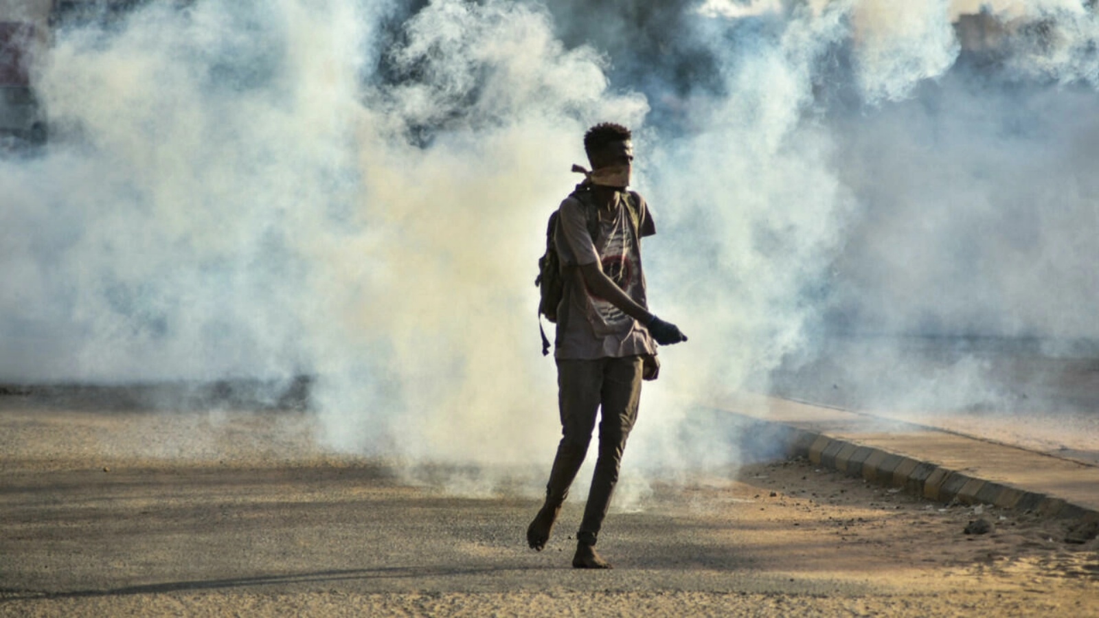 شاب سوداني يتنقل حافي القدمين وسط قنابل مسيلة للدموع أطلقتها قوات الأمن في العاصمة الخرطوم. في 27 تشرين الأول/أكتوبر 2021.