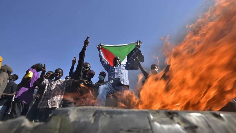 رحل يحمل علم السودان عند حاجز أضرمت فيه النار إلى شرق الخرطوم في 13 نوفمبر 2021 وسط احتجاجات ضد الانقلاب العسكري في السودان