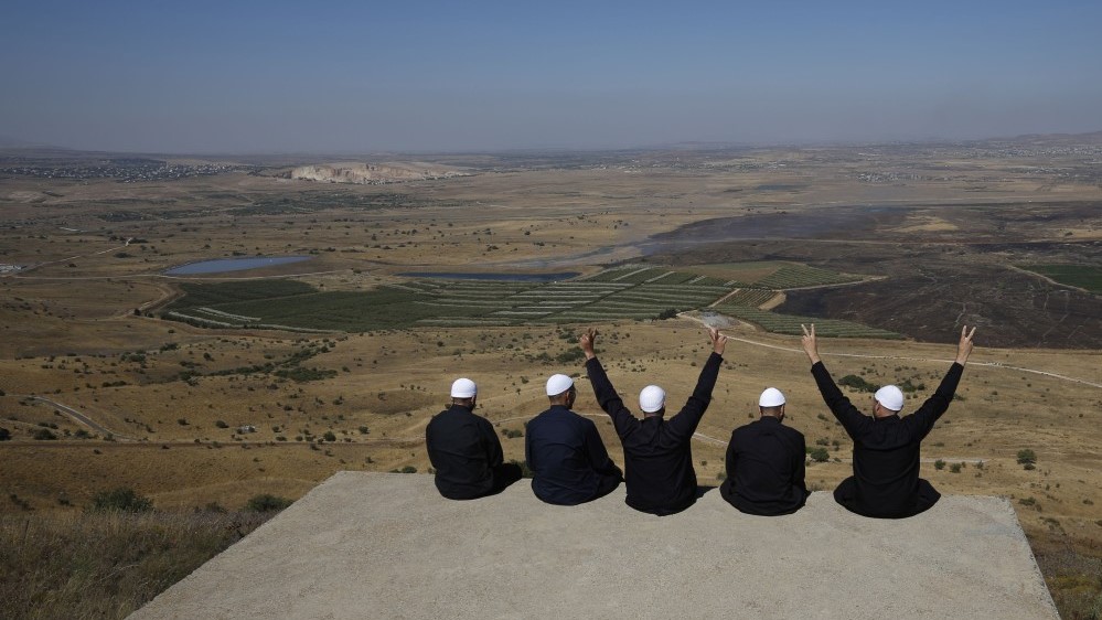 دروز في مرتفعات الجولان التي ضمتها إسرائيل يرفعون علامة النصر وهم ينظرون إلى القنيطرة جنوب غرب سوريا، في7 يوليو 2018