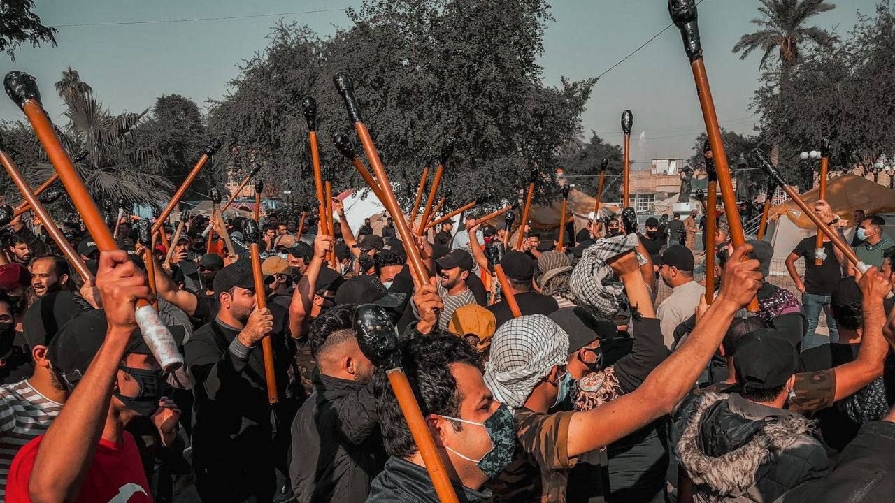 انصار القوى العراقية المقربة من إيران الخاسرة للانتخابات يلوحون بالهراوات للقوات الامنية امام المنطقة الخضراء الجمعة 26 تشرين الثاني نوفمبر 2021