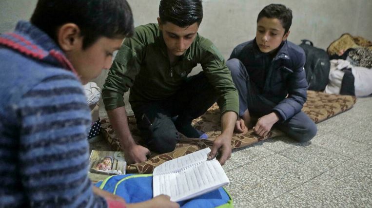 الطفل السوري محمد مخزوم يساعد شقيقيه في واجباتهم المنزلية في مدينة الباب في شمال سوريا في 19 نوفمبر 2021
