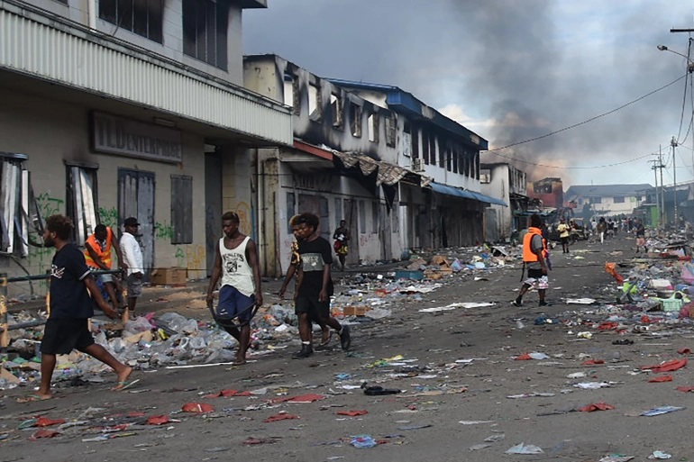 الناس يسيرون في الحي الصيني في هونيارا في جزر سليمان في 26 تشرين الثاني/ نوفمبر 2021، بعد يومٍ ثالث من العنف الذي شهد هجومًا على منزل رئيس الوزراء