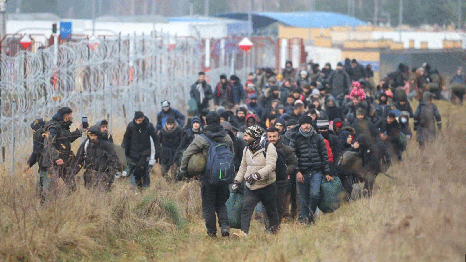 مجموعة من المهاجرين تتحرك على طول الحدود البيلاروسية البولندية نحو معسكر للانضمام إلى أولئك الذين تجمعوا في الحال بهدف دخول بولندا العضو في الاتحاد الأوروبي، في منطقة هرودنا. 12 تشرين الثاني/نوفمبر 2021