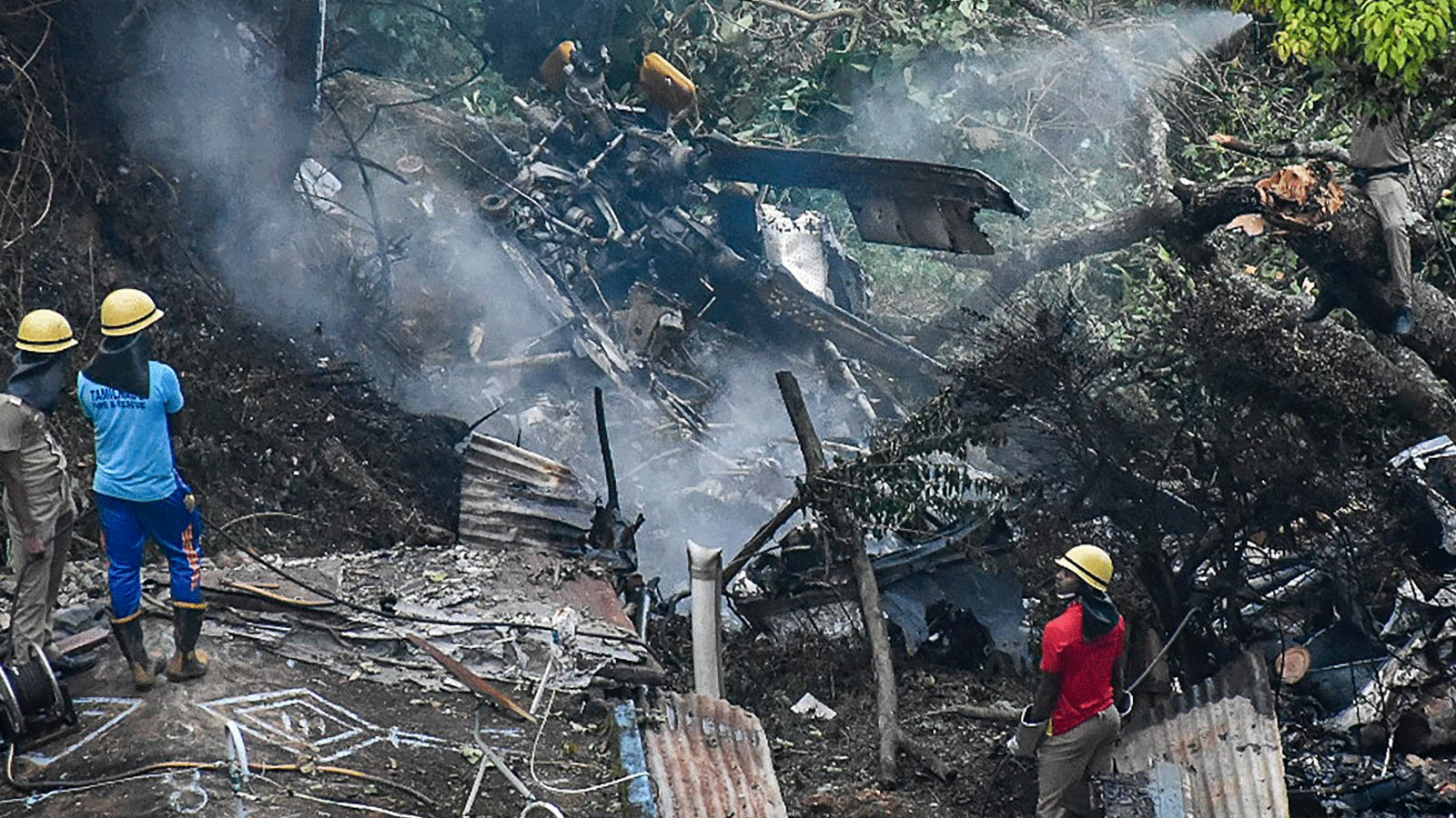 رجال الإطفاء وعمال الإنقاذ يقفون بجانب حطام موقع تحطم طائرة هليكوبتر تابعة لسلاح الجو الهندي من طراز Mi-17V5 في كونور، تاميل نادو، الهند. 8 كانون الأول/ديسمبر 2021 