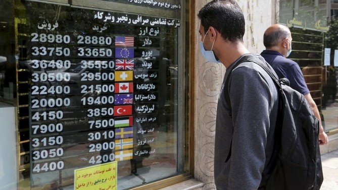 إيراني يفحص لوحة عرض في محل صرافة في العاصمة طهران