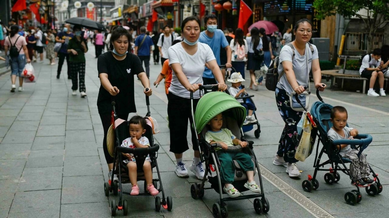 ثلاث نساء يسرن مع عربات أطفال في بكين في 13 تموز/يوليو 2021 