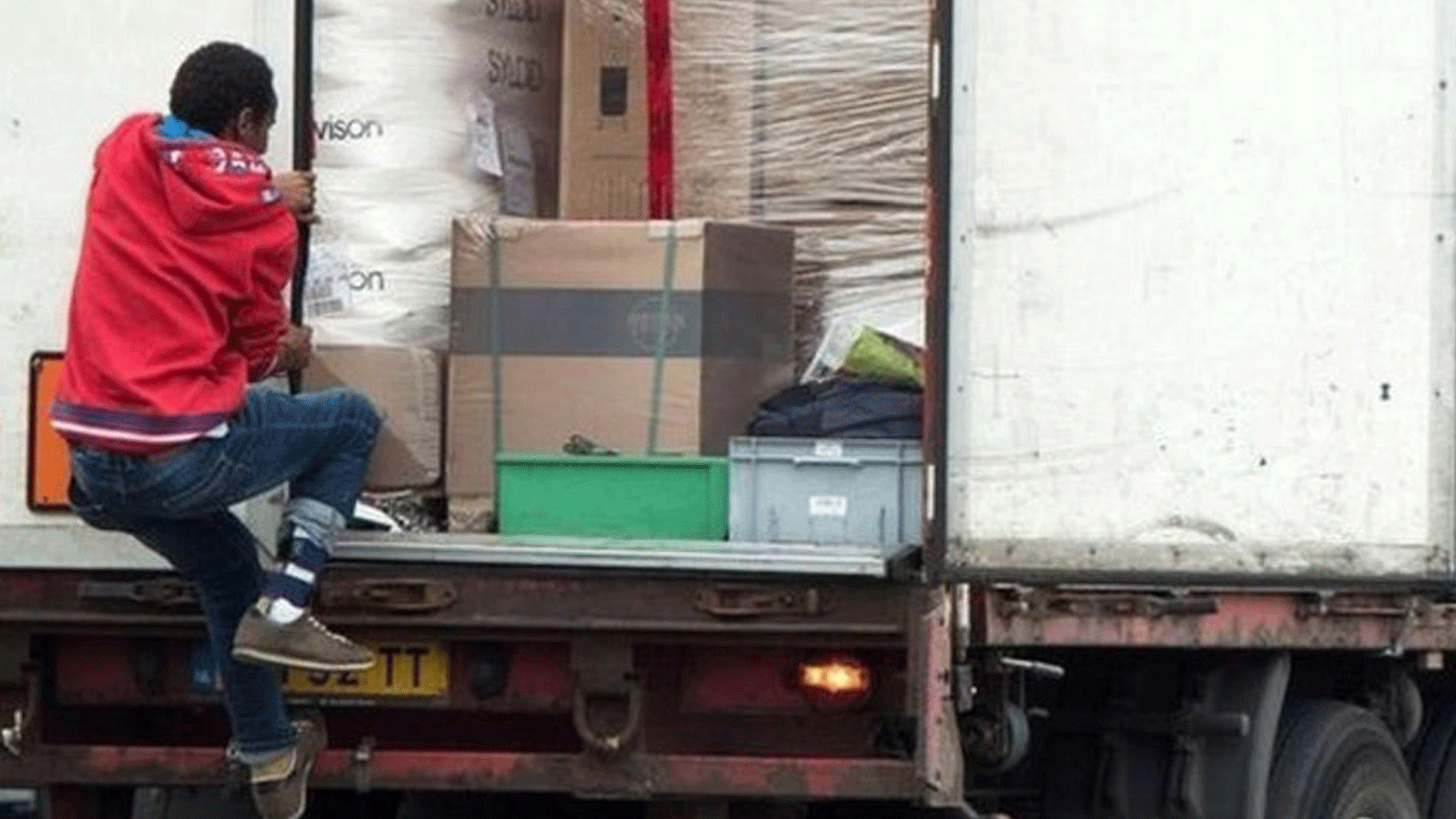 مهاجر يتسلق شاحنة محاولاً الوصول إلى المملكة المتحدة عبر كاليه مع فرار الناس من الأزمات الإنسانية