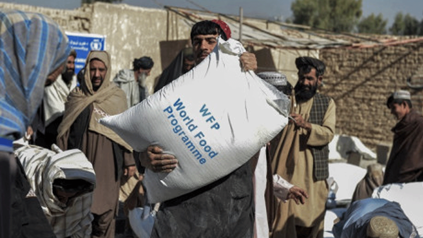 صورة التُقِطَت في 19 أكتوبر / تشرين الأول 2021 لأفغان يحملون أكياس حبوب وزّعها برنامج الغذاء العالمي في قندهار بأفغانستان كمساعدات