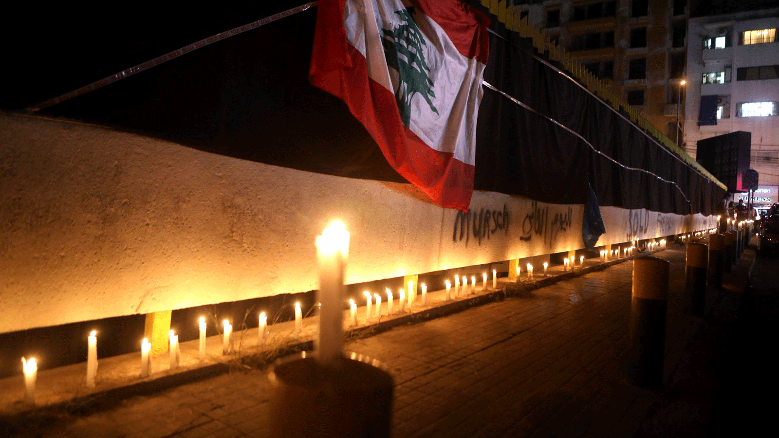 العلم اللبناني معلق على جدران مقر شركة الكهرباء مغطى بأقمشة سوداء بينما يشارك المتظاهرون في وقفة احتجاجية على ضوء الشموع في بيروت في 11 تشرين الثاني /نوفمبر 2020