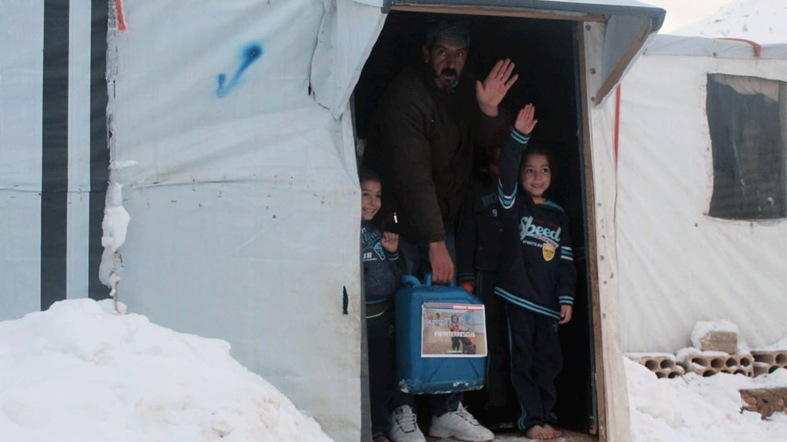 صورة من صفحة (اتحاد جمعيات الإغاثة والتنمية/ URDA) لرجل يحمل المازوت إلى خيمته مع أولاده في المخيم السوري ببلدة عرسال