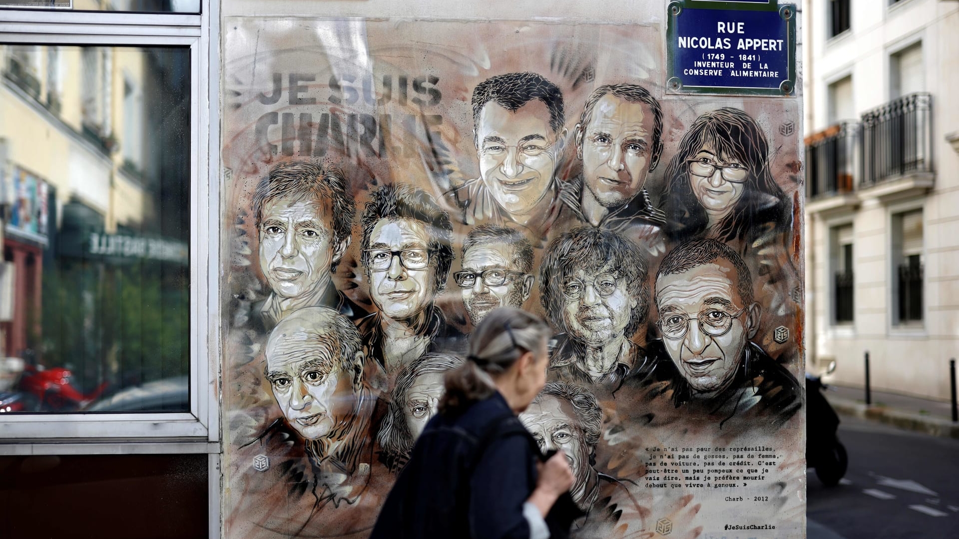 سيدة تمر بجوار لافتة تحيي ذكرى الضحايا في الهجوم على مقر صحيفة شارلي إبدو الفرنسية في 2015