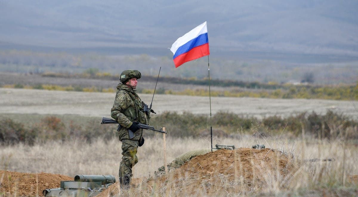 جندي روسي إلى جوار علم بلاده في صورة أرشيفية