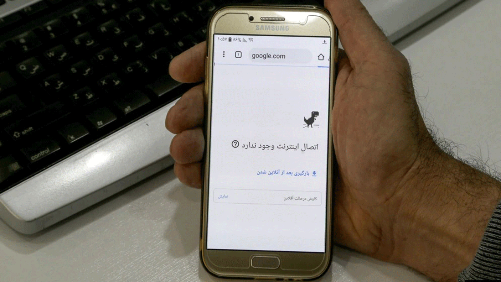 رجلٌ يحمل هاتفًا ذكيًا متصلًا بشبكة WiFi بدون اتصال بالإنترنت في مكتب بطهران في 17 تشرين الثاني/ نوفمبر.
