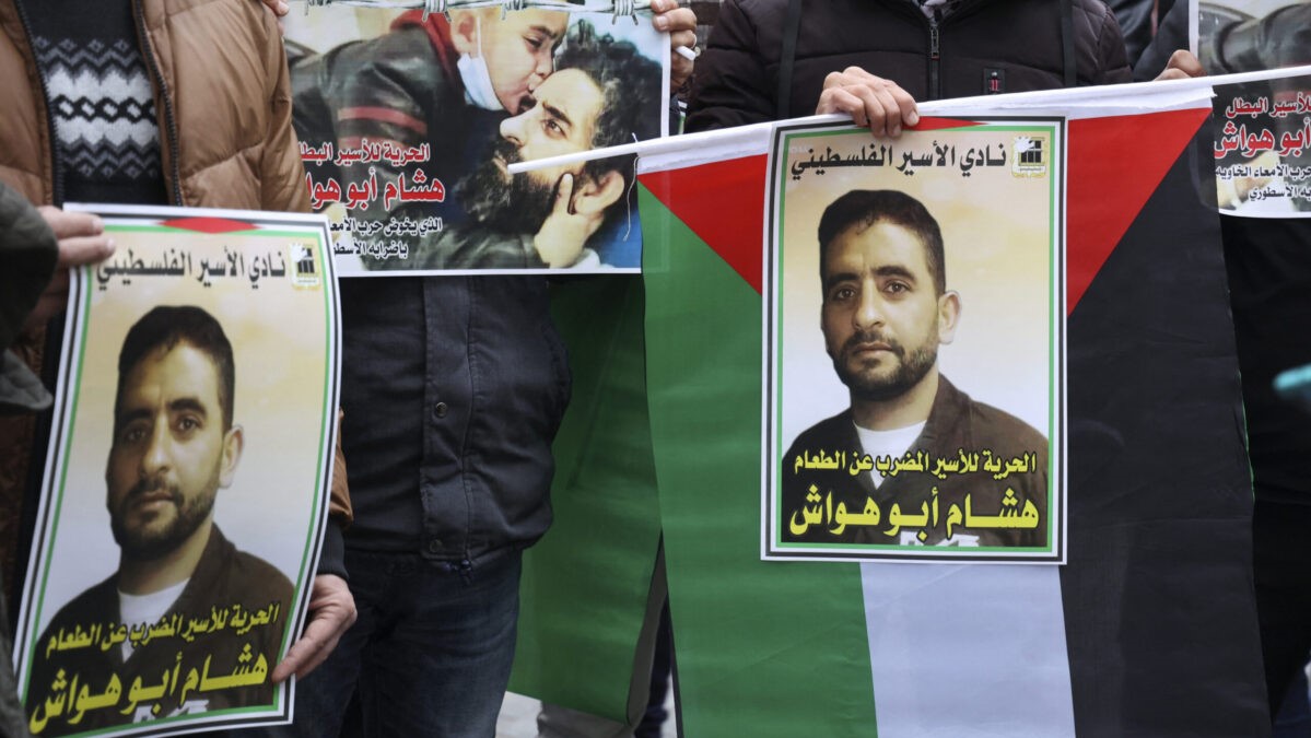 فلسطينيون يرفعون لافتات أثناء تجمعهم دعما للأسير الفلسطيني المضرب عن الطعام هشام أبو هواش في مدينة نابلس شمال الضفة الغربية المحتلة في 4 يناير 2022