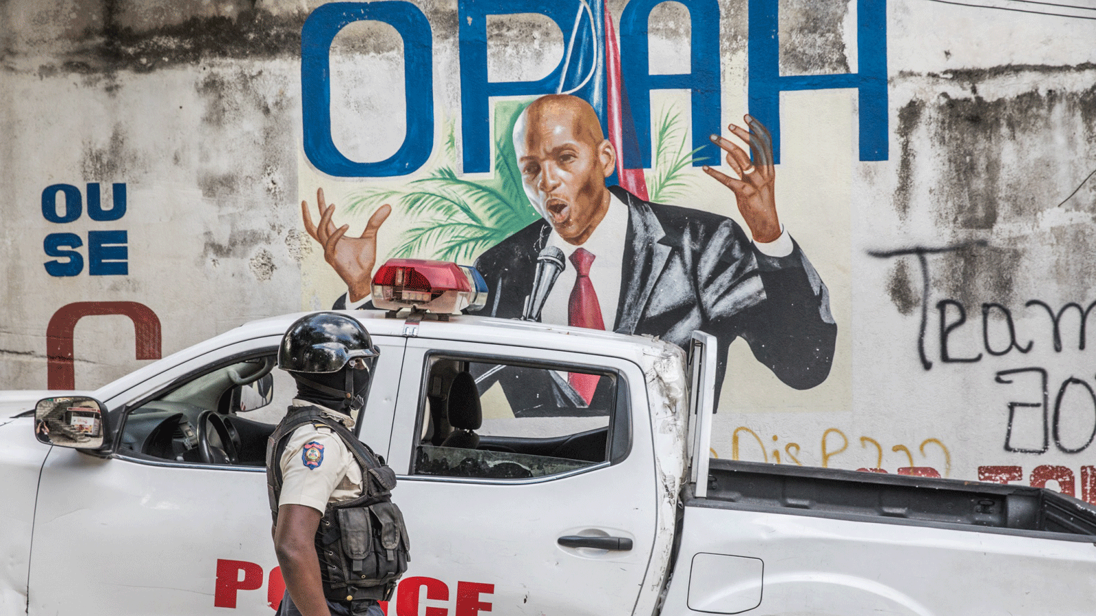 ضابط شرطة يقف بجانب جدارية للرئيس الهايتي الراحل جوفينيل مويس بعد اغتياله في بورت أو برنس في 15 تموز/يوليو 2021 