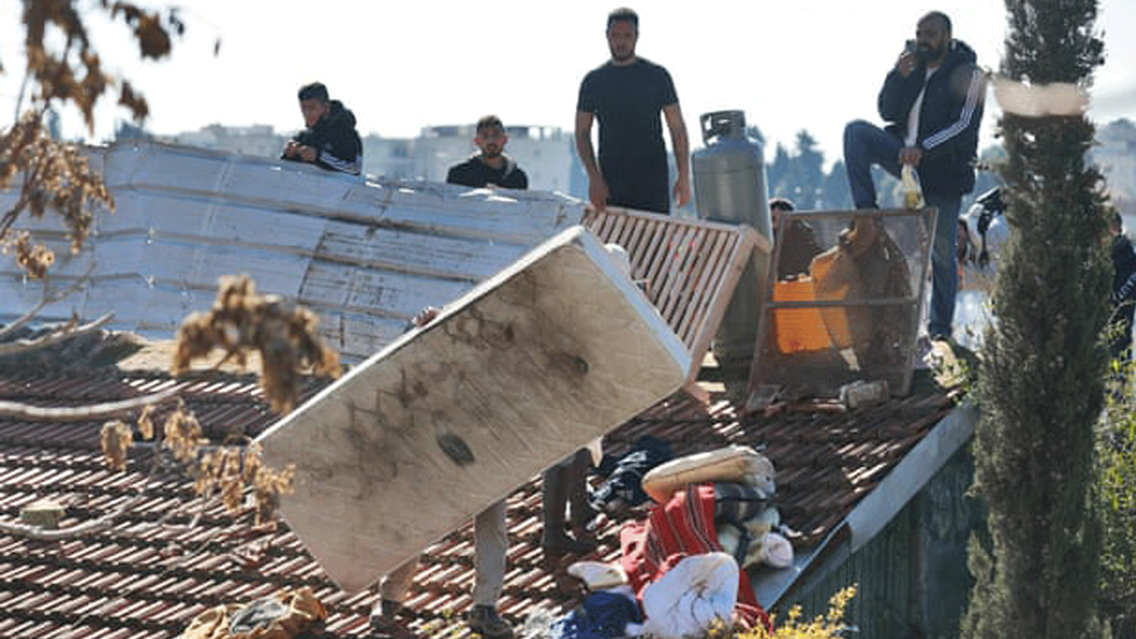 رجال فلسطينيون يحاصرون أنفسهم فوق سطح منزل في الشيخ جراح بالقدس، بينما تستعد الشرطة الإسرائيلية لإجلاء عائلة من نفس المبنى