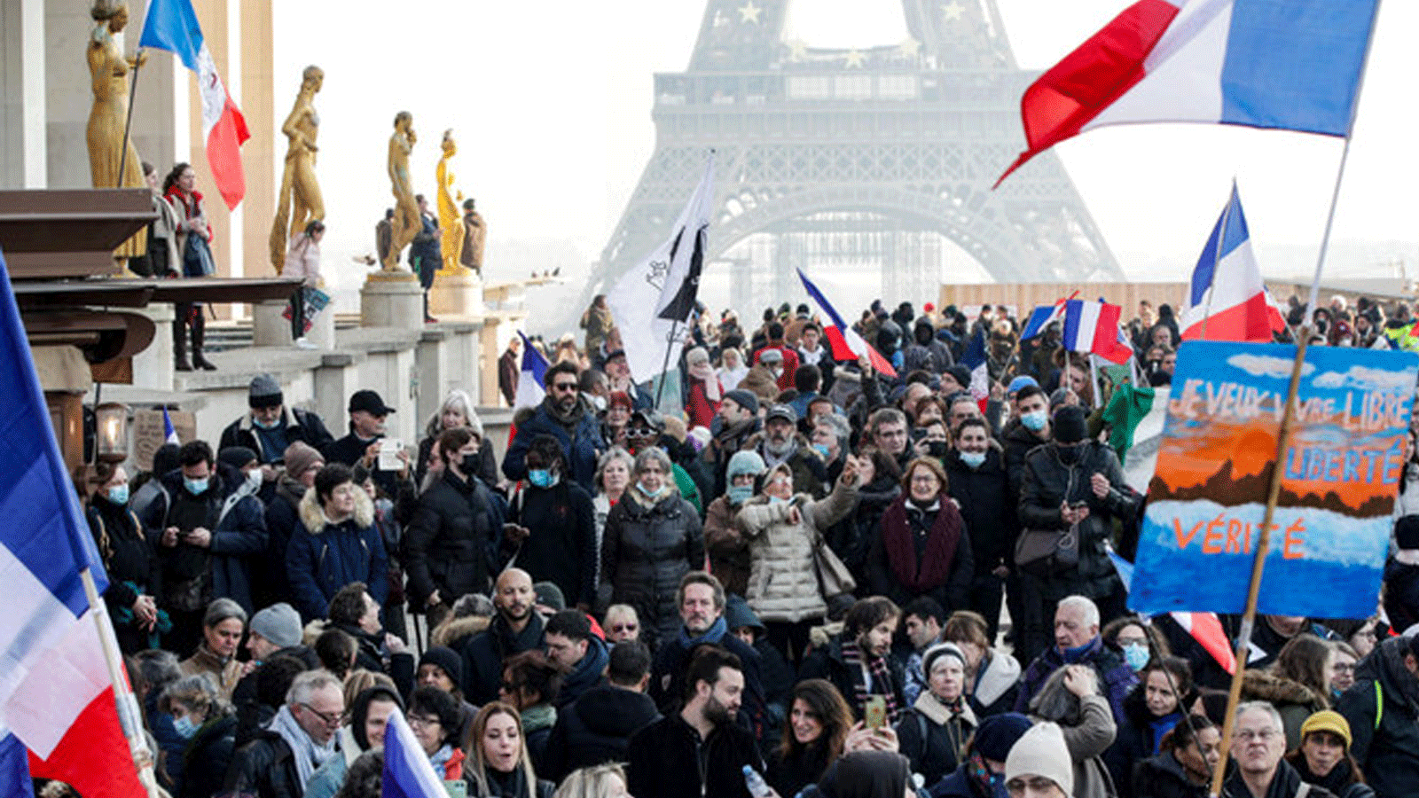 متظاهرون يحملون لافتات وطلاءات غازية فرنسية خلال مظاهرة ضد بطاقة الصحة ولقاحات Covid-19، في ساحة تروكاديرو في باريس. 15 كانون الثاني/ يناير 2022.