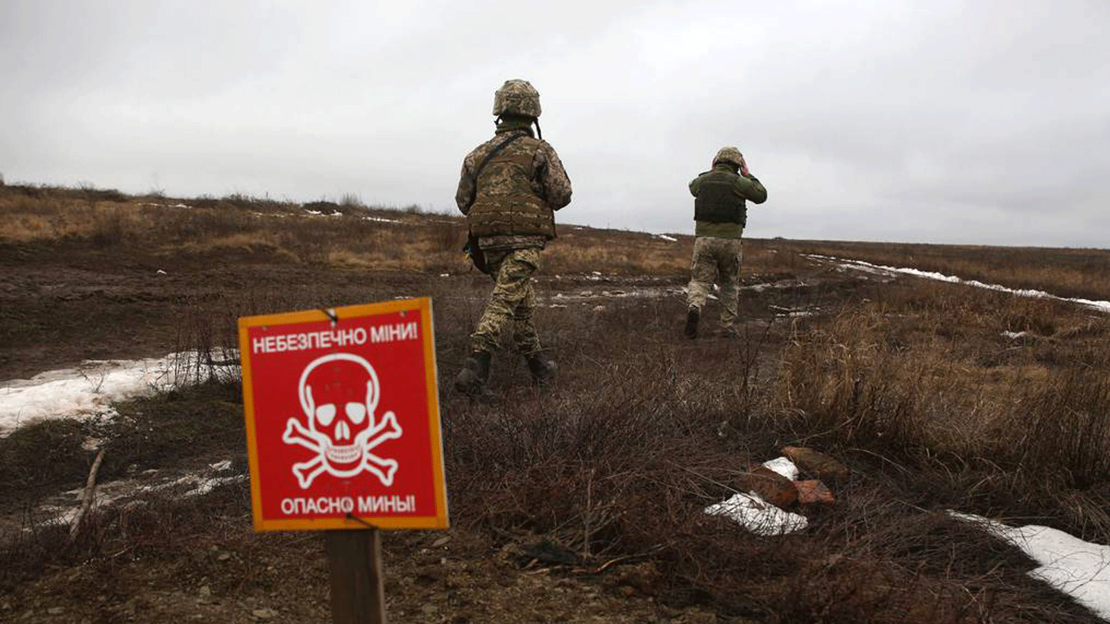 جنود من القوات العسكرية الأوكرانية يمرون عبر لوحة معدنية كُتِب عليها 