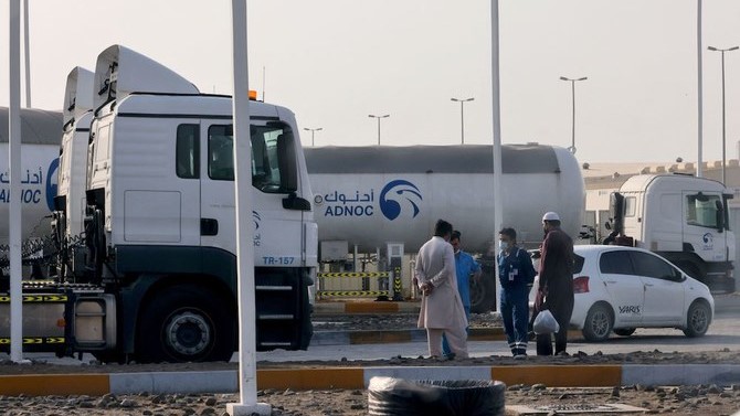 رجال يقفون خارج منشأة تخزين تابعة لشركة أدنوك في أبو ظبي ، في 17 يناير 2022. قُتل ثلاثة أشخاص في هجوم يشتبه أنه بطائرة مسيرة على منشآت أدنوك يوم الاثنين.
