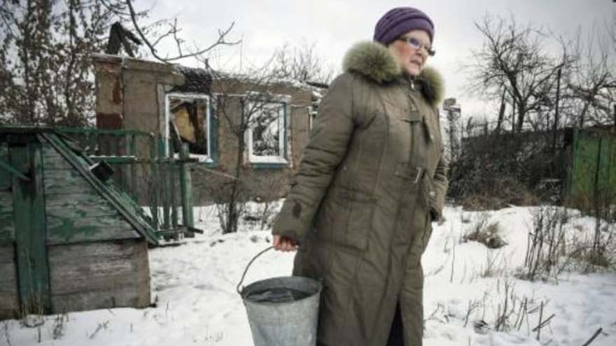 إحدى سكان دونيتسك تمر أمام منزل مدمر في 18 كانون الثاني/يناير 2022