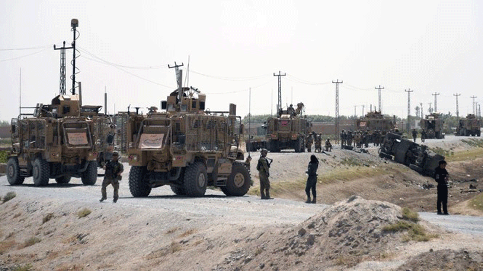 جنود الناتو يراقبون بالقرب من حطام سيارتهم في موقع هجوم انتحاري لطالبان في قندهار.