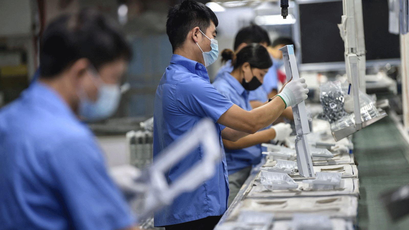 عمال ينتجون قطع غيار الغسالات في مصنع في نانجينغ، مقاطعة جيانغسو الشرقية، الصين، في 16 آب/ أغسطس 2021